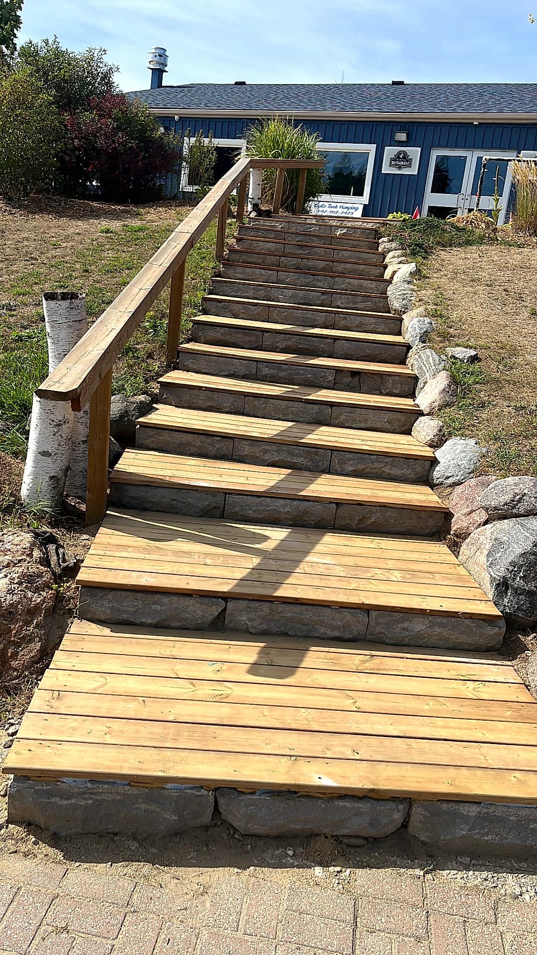 Armour stone staircase with cedar treads and a timber handrail built up a graded slope