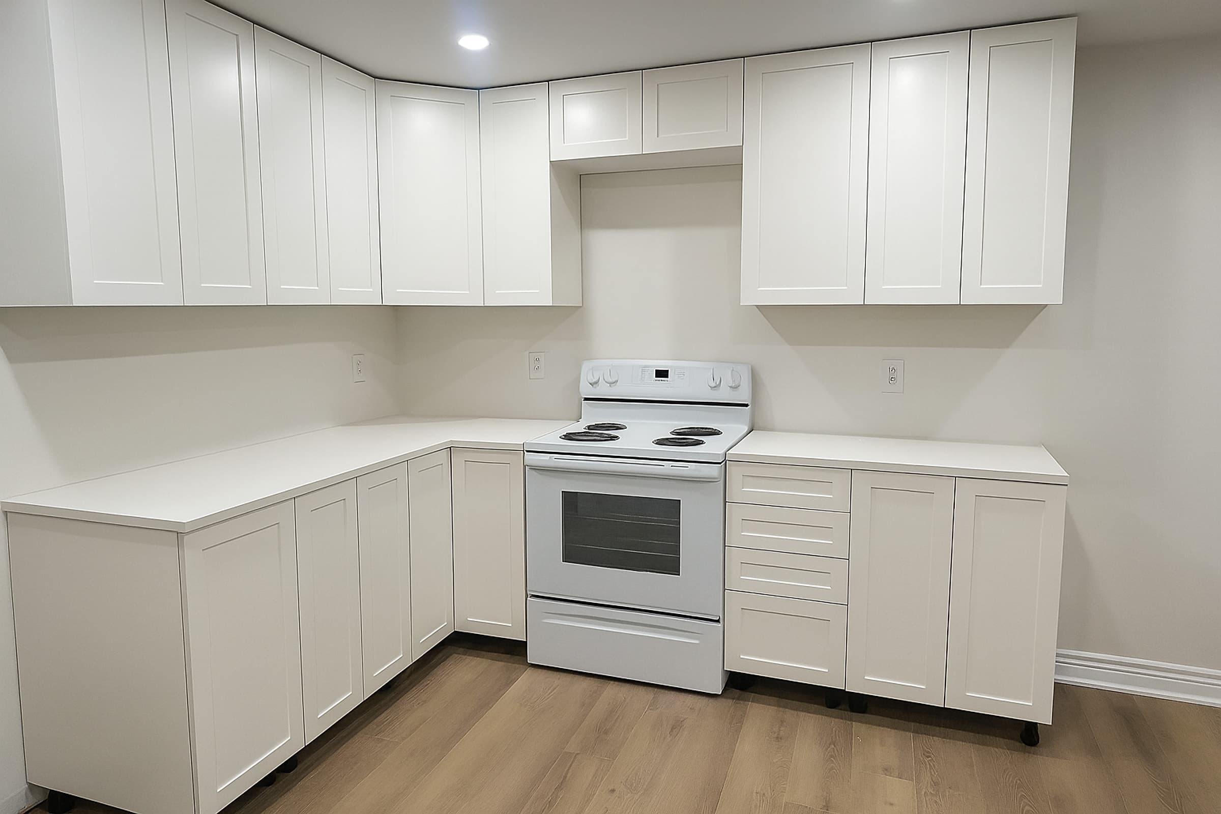 Basement suite kitchen with white shaker cabinets, white countertop, range and vinyl plank flooring