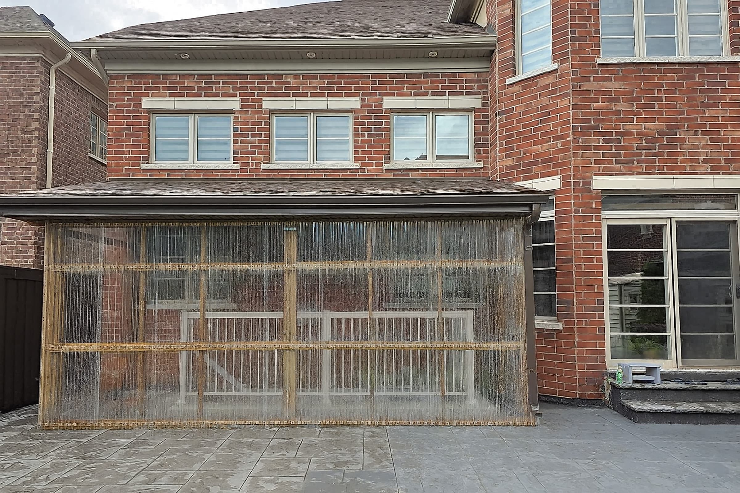 Rear porch enclosed with a timber frame and clear corrugated polycarbonate panels under a shingled roof